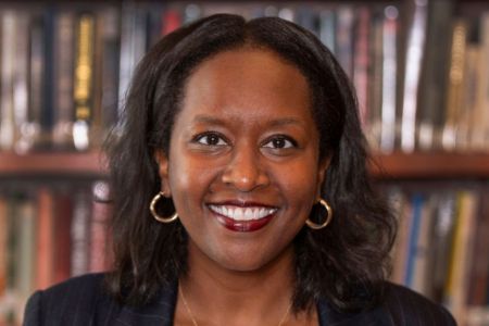 Headshot of Meseret Hailu in front of bookshelves