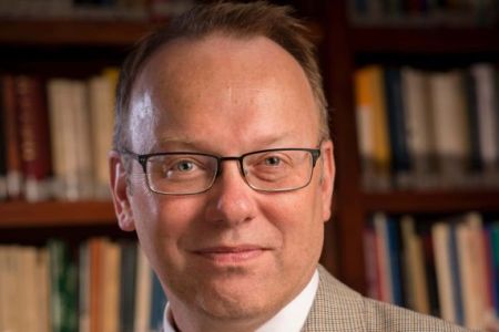headshot of tim cain in front of bookcases